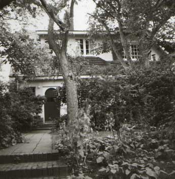 [a picture of the back of a house between trees and bushes]